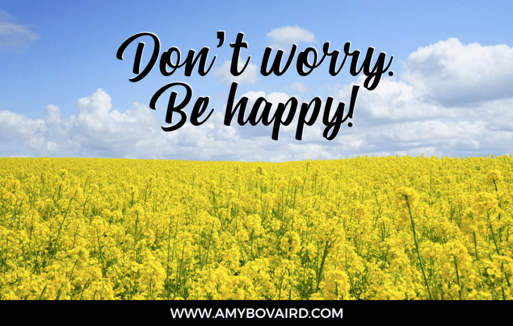 Amy Bovaird says Dont-worry-be-happy. picture of a yellow wild flower field and blue sky with white clouds.