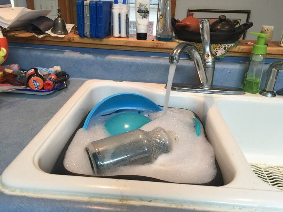 Amy Bovaird Water Almost Did Me In Today. A picture of a sink full of dishes with water running and soap suds.