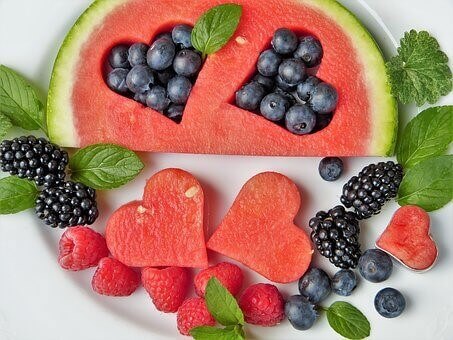 picture of juicy seasonal fruits - watermelon cut in heart shapes, black and red raspberries, blueberries