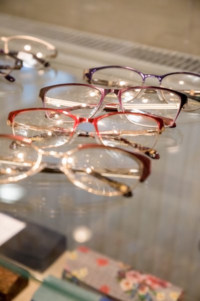 Many glasses rows at optical retail store. Rich assortment choice of different eyewear frames on eyeglasses shop display.optical shop.Row with colorful modern eyeglasses