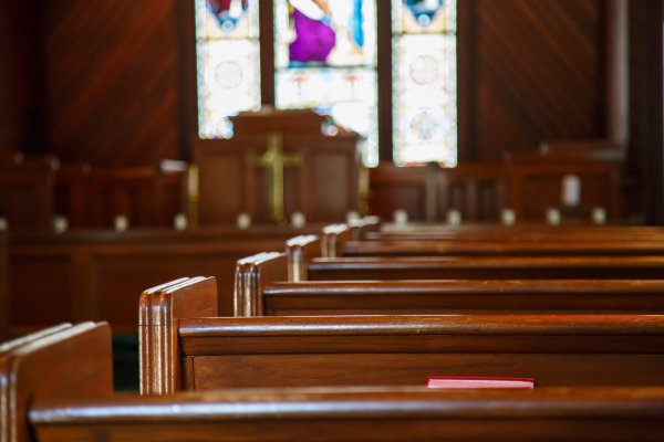 Pictuire of stained glass windows in small church with wood pews